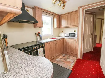 a kitchen with wooden cabinets and a stove top oven at 1 Old Orchard in Much Wenlock