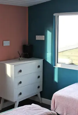 a bedroom with a white dresser and a window at Redwood Lodge, Dee Valley Stays - cosy microlodge with detached private shower & WC in Corwen