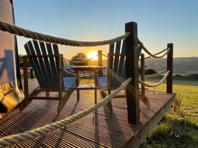 a deck with two chairs and a table with the sunset at Heart of the Wye in Clifford