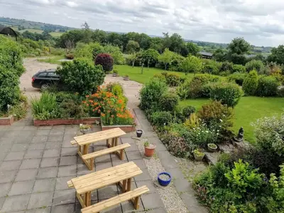 a garden with two wooden benches and flowers at Country Home with Gardens in Newtown