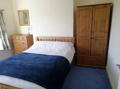 a bedroom with a bed and a wooden cabinet at Country Home with Gardens in Newtown