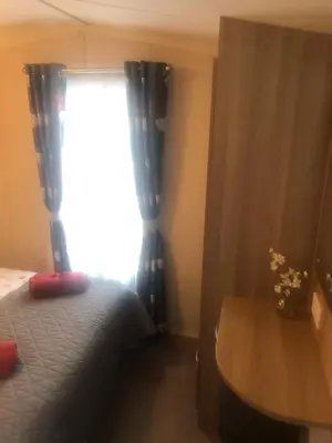 a bedroom with a bed and a window with curtains at Cosy holiday caravan minutes from the beach in Aberystwyth