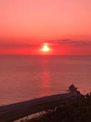 a sunset over the ocean with a beach in the foreground at Cosy holiday caravan minutes from the beach in Aberystwyth