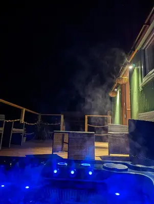 a deck with a table and chairs at night at Bespoke luxury huts with hot tubs. Located in the black mountains. in Llanveynoe