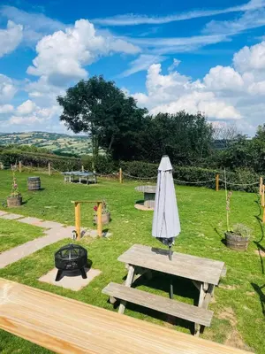 a picnic table with an umbrella and a grill at Bespoke luxury huts with hot tubs. Located in the black mountains. in Llanveynoe