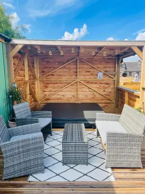 a patio with wicker chairs and a wooden fence at Bespoke luxury huts with hot tubs. Located in the black mountains. in Llanveynoe