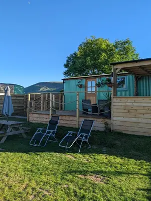 two chairs and an umbrella in a yard with a house at Red darren luxury hut in Llanveynoe