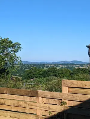 a wooden fence with a view of the countryside at Red darren luxury hut in Llanveynoe
