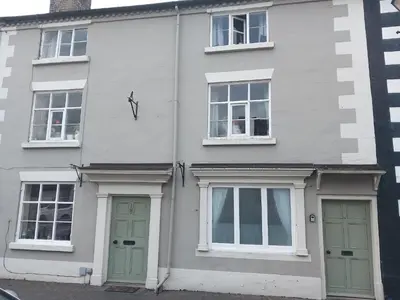 a white house with green doors and windows at self contained flat in Llanfyllin Powys in Llanfyllin