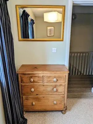 a dresser in a bedroom with a mirror on the wall at The Cob House. in Ifton Heath