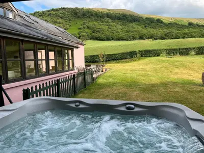 a hot tub in the backyard of a house at Baddegai Holiday Cottage in Brecon