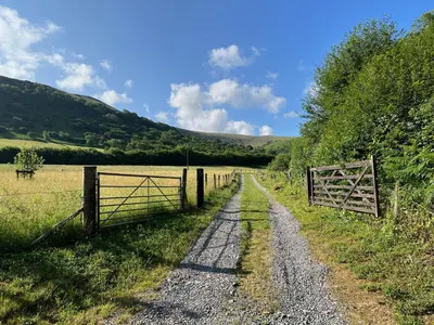 a dirt road in a field with a fence at Baddegai Holiday Cottage in Brecon