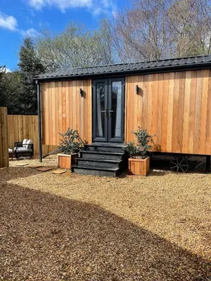 a wooden house with a black door and some plants at Berwyn Lodge with private hot tub in Llangollen