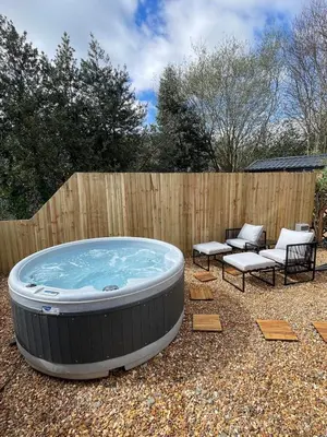a hot tub in a yard with chairs and a fence at Berwyn Lodge with private hot tub in Llangollen