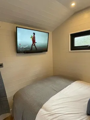 a bedroom with a bed and a tv on the wall at Berwyn Lodge with private hot tub in Llangollen