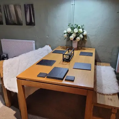 a wooden table with a vase of flowers on it at The Granary Corris on the edge of the Dyfi Forest in Corris