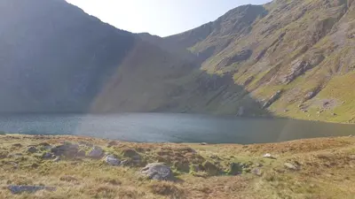 a rainbow over a lake in a mountain at The Granary Corris on the edge of the Dyfi Forest in Corris