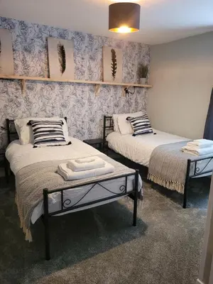two beds in a room with blue wallpaper at Ty Golchi - Cosy traditional cottage in Corris in Corris