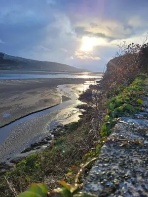 a view of a beach with the sun in the distance at Ty Golchi - Cosy traditional cottage in Corris in Corris