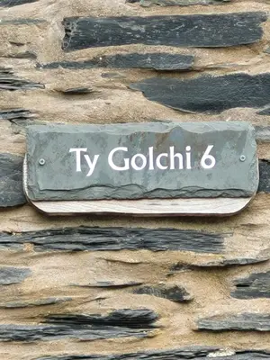 a sign on the side of a stone wall at Ty Golchi - Cosy traditional cottage in Corris in Corris