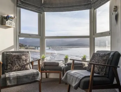 a room with two chairs and a table and a large window at Harbour View - Flat 2 - Tudor House in Barmouth
