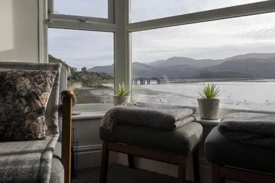 a window with two chairs and a view of the water at Harbour View - Flat 2 - Tudor House in Barmouth