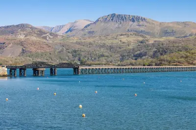 a bridge over a body of water with mountains in the background at Harbour View - Flat 2 - Tudor House in Barmouth