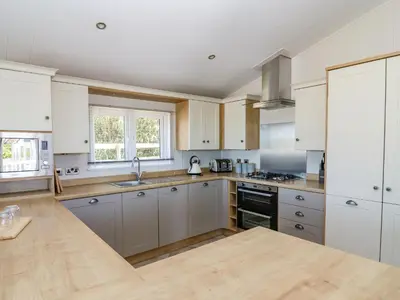 a large kitchen with white cabinets and a sink at Ystwyth 36 in Borth