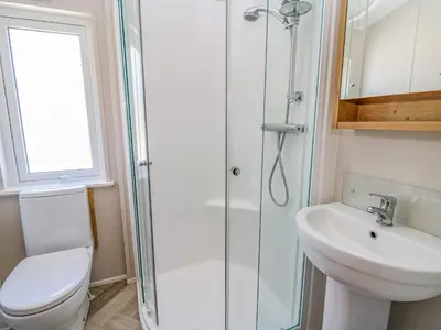 a bathroom with a shower and a toilet and a sink at Ystwyth 36 in Borth