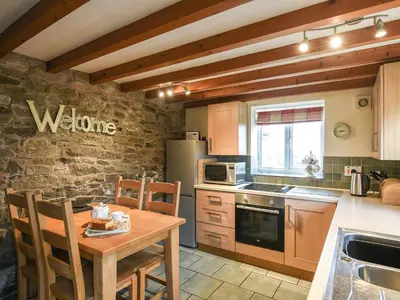 a kitchen with a wooden table and a kitchen with a refrigerator at Heron Cottage in Bishops Castle