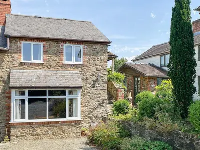 a stone house with a large window at Curlew Cottage in Bromlow