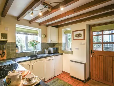 a kitchen with a counter and a door and some windows at Curlew Cottage in Bromlow