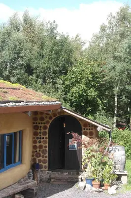 a stone building with a black door and trees at Sapphire forest garden shepherd’s hut in Church Stretton