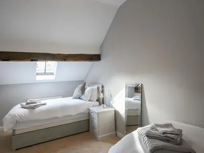 a white bedroom with a bed and a mirror at Grove Farm Cottage in Condover