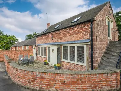 a brick house with a patio in front of it at Grove Farm Cottage in Condover