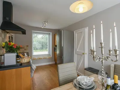 a kitchen and dining room with a table and a refrigerator at Grove Farm Cottage in Condover