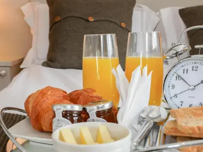 a breakfast tray with bread and orange juice on a bed at Grove Farm Cottage in Condover