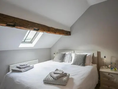 a bedroom with a white bed with towels on it at Grove Farm Cottage in Condover