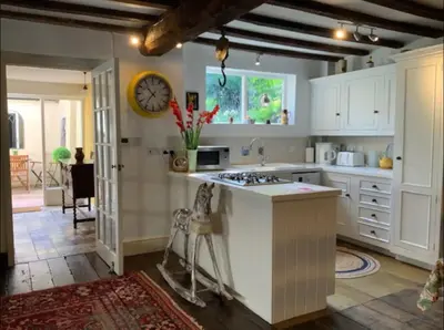 a kitchen with white cabinets and a clock on the wall at Magical period house in the heart of Ludlow - Pass the Keys in Ludlow