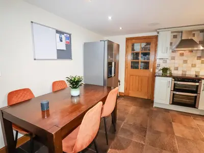 a kitchen and dining room with a wooden table and chairs at Tyn Y Ceubren Bach at Evelyns Retreat in Corwen