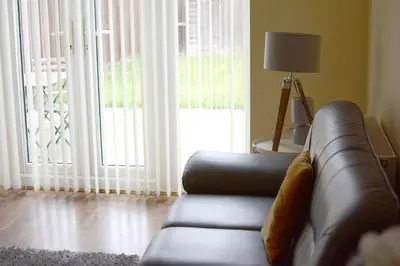 a living room with a leather couch and a window at Family home close to Shrewsbury Town centre in Shrewsbury