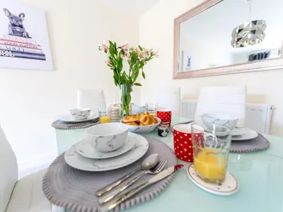 a table with plates and cups and a vase with flowers at Stylish modern two bedroom home in Shrewsbury - Pass the Keys in Shrewsbury