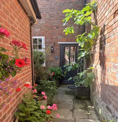 an entrance to a brick building with flowers and a door at The Gardener's Cottage in Leominster