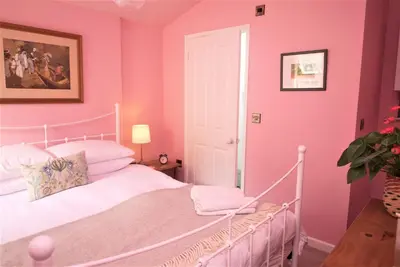 a bedroom with pink walls and a white bed at The Gardener's Cottage in Leominster
