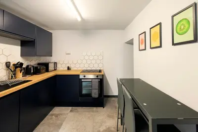 a kitchen with blue cabinets and a black table at Seafront apartment with balcony, parking and sea views in Aberystwyth