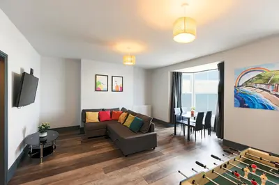 a living room with a couch and a table at Seafront apartment with balcony, parking and sea views in Aberystwyth