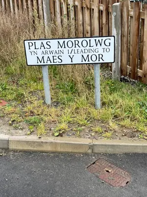 a sign sitting on the side of a street at The New 2 Plas Morolwg in Aberystwyth