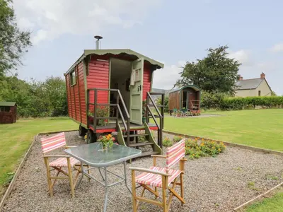 a small red house with a table and chairs at Tilly Gypsy-style Caravan Hut in Brecon