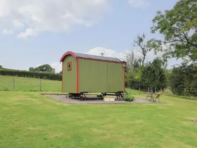 a green and red shed sitting in a field at Sweet Briar Shepherds Hut in Brecon