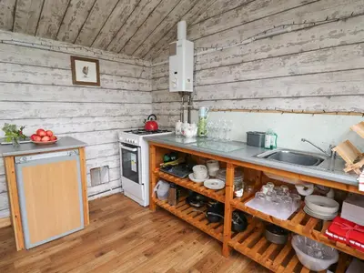 a kitchen with wooden walls and a counter with a sink at Sweet Briar Shepherds Hut in Brecon